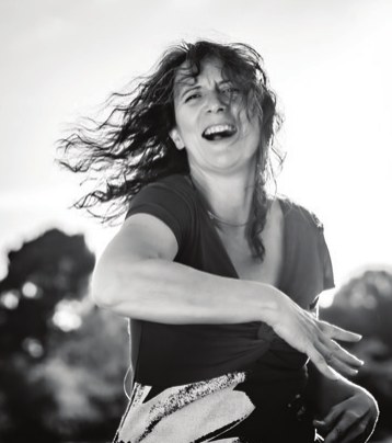Lucie Nerot dancing outdoors, laughing, hair in motion